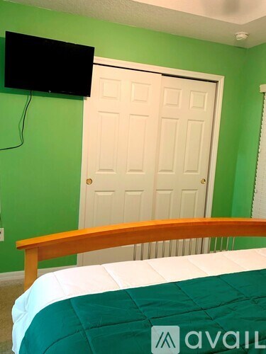 A bedroom with a bed, a television, and a door.