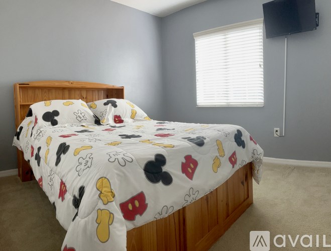 A bed with a white comforter and a wooden headboard is in a room with a window.