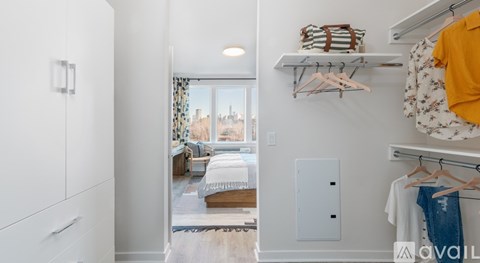 A bedroom with a bed and a window overlooking a cityscape.