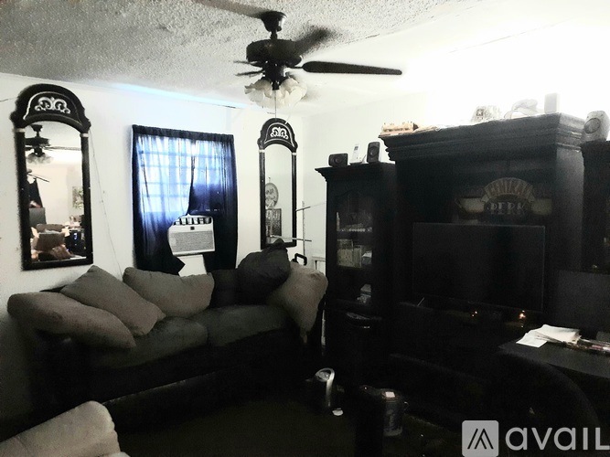 A living room with a couch, a television, and a ceiling fan.