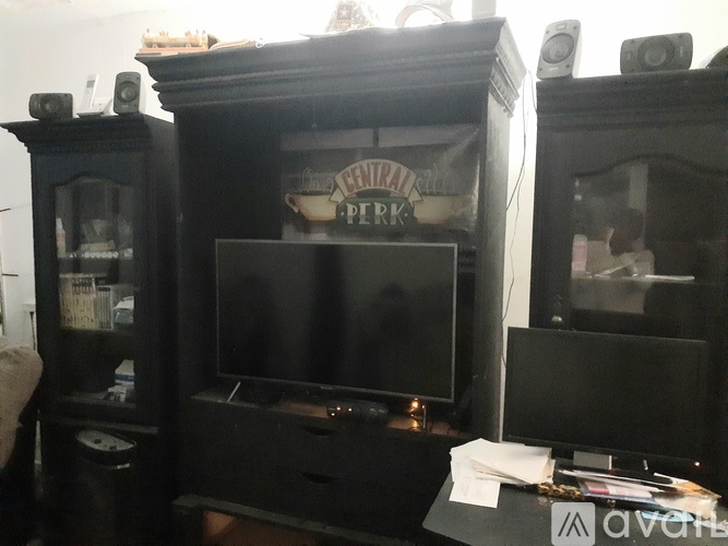 A black entertainment center with a television and speakers.