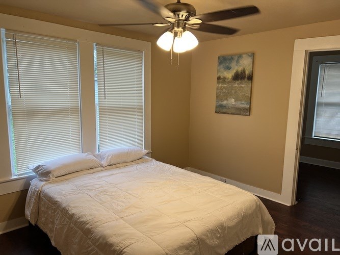 A bedroom with a bed, a ceiling fan, and a painting on the wall.