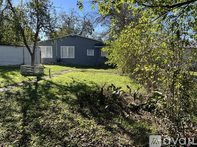 A small house with a grey roof and a tree in front of it.