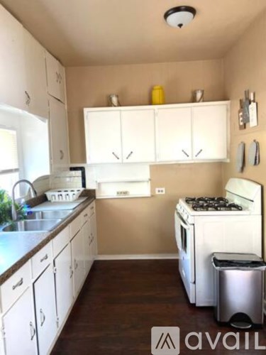 A kitchen with white cabinets and a stove top oven.