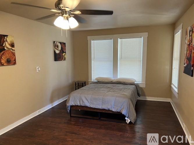 A bedroom with a bed, a ceiling fan, and two pictures on the wall.