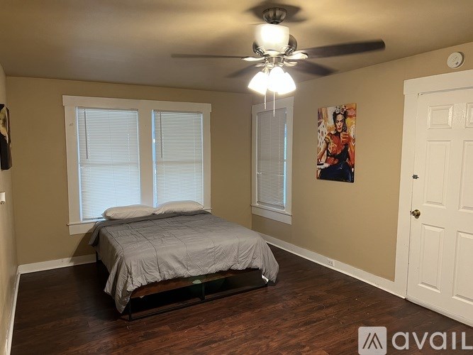 A bedroom with a bed, a ceiling fan, and a window.