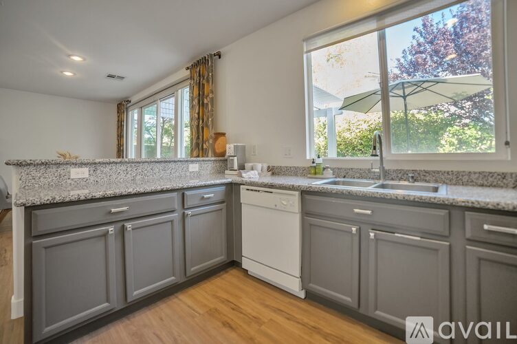 A kitchen with a white dishwasher and grey cabinets.