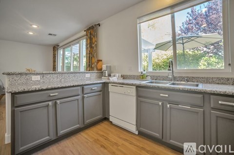 A kitchen with a white dishwasher and grey cabinets.