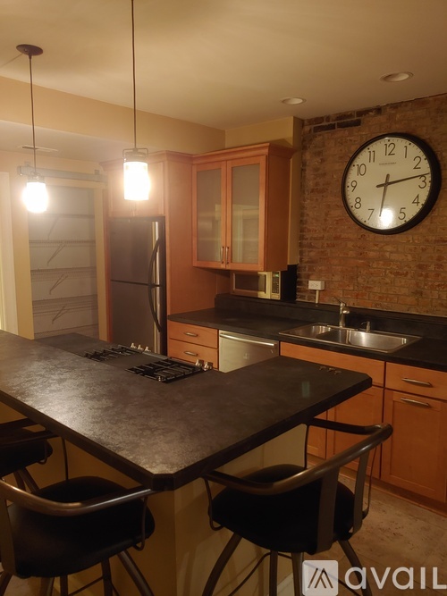 A kitchen with a black table and a brick wall clock.