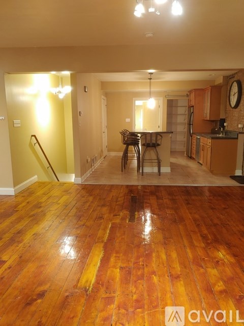 A living room with a wooden floor and a bar area.