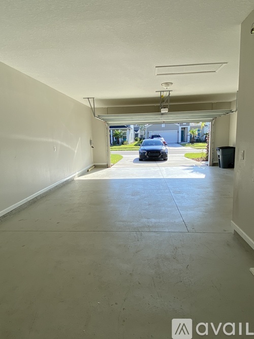 A car is parked in a garage with a white wall on the left side.