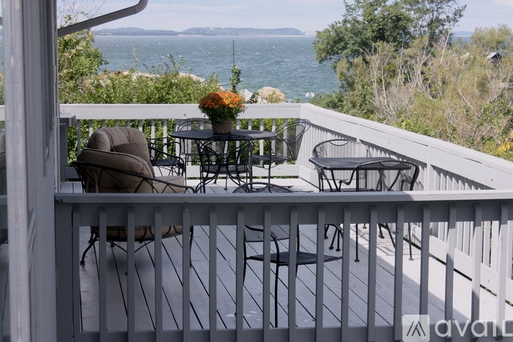 A patio with a table and chairs overlooking the water.