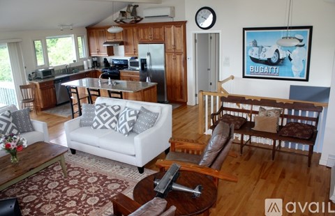 A living room with a white couch and a painting of a boat on the wall.