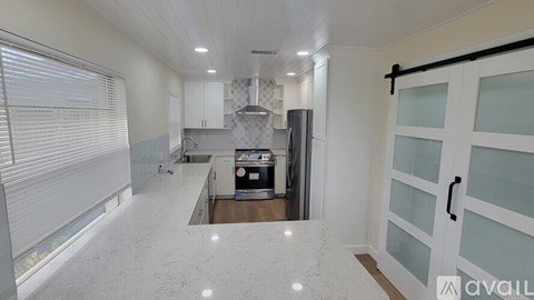 A kitchen with white cabinets and a marble countertop.