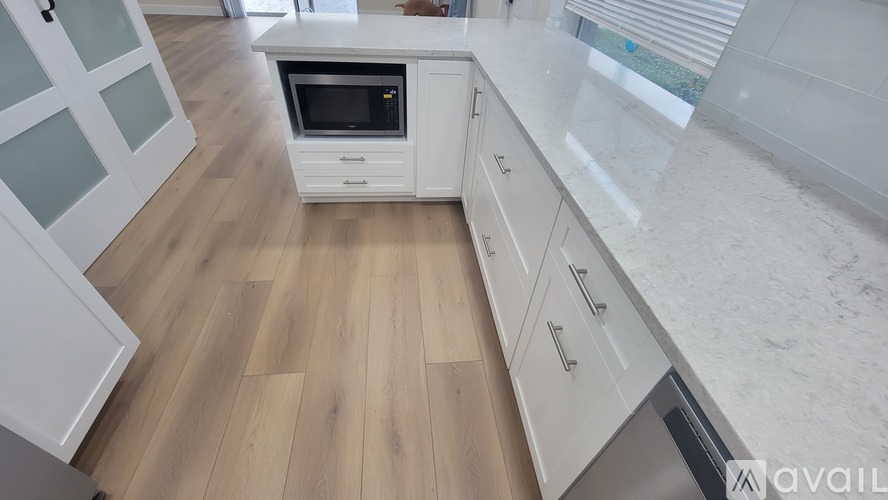 A kitchen with a white countertop and wooden flooring.