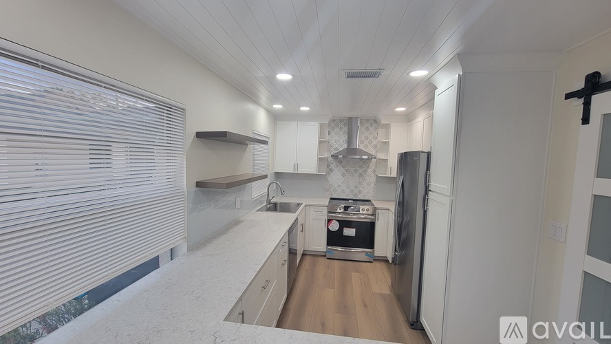 A kitchen with white cabinets and a black fridge.