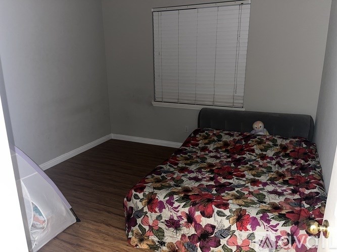 A bed with a floral comforter sits in a room with a window.