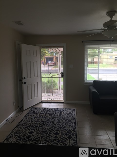 A living room with a black couch and a patterned rug.
