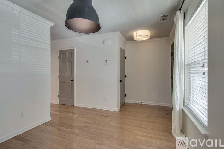 A room with a wooden floor and a grey pendant light hanging from the ceiling.