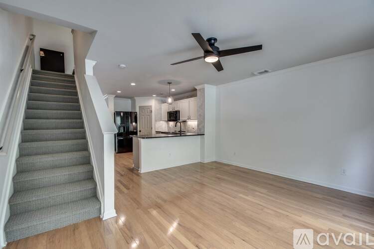 A spacious room with a staircase and a ceiling fan.