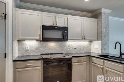 A kitchen with a black microwave above a stove.