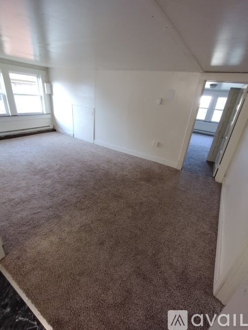 A room with carpeted floor and a window letting in light.