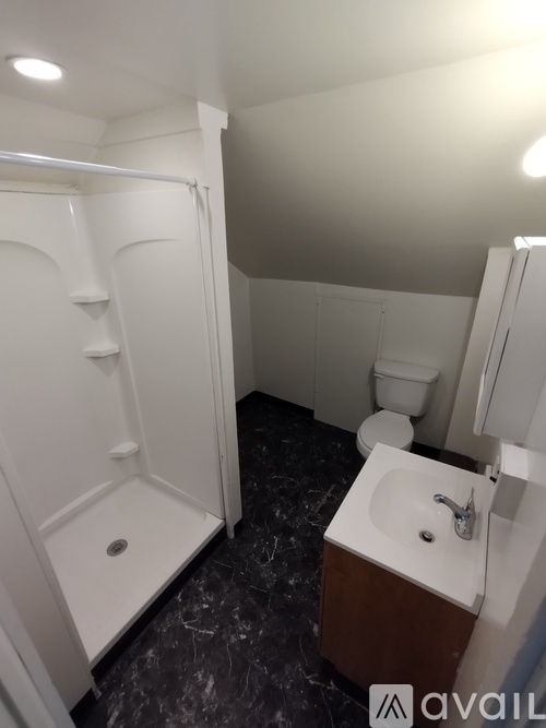 A bathroom with a white shower stall, toilet, and sink.