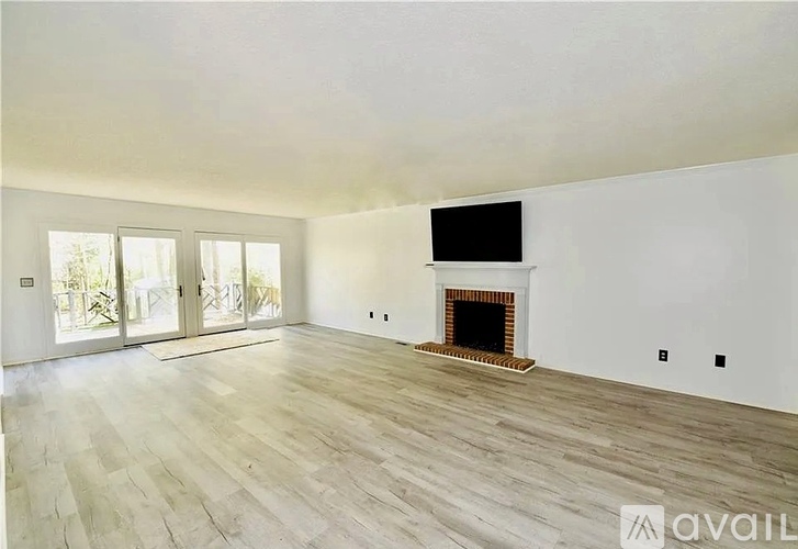 A living room with a fireplace and a flat screen TV mounted on the wall.