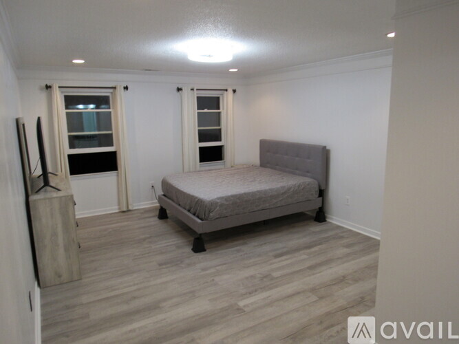 A bedroom with a bed, nightstand, and window.