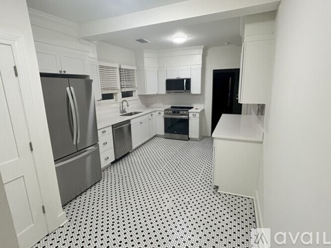 A kitchen with white cabinets and black and white floor tiles.