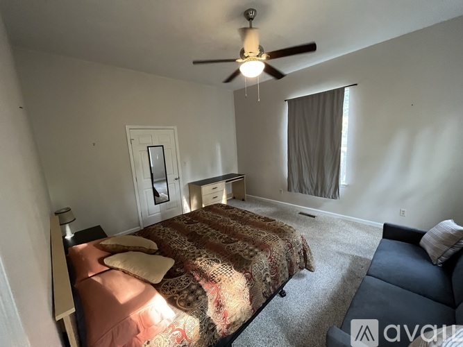 A bedroom with a bed, a couch, and a ceiling fan.