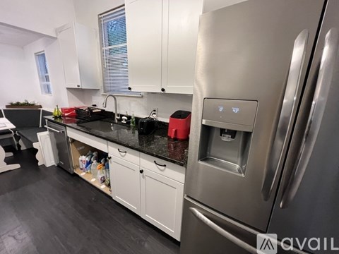 A modern kitchen with a stainless steel refrigerator and white cabinets.