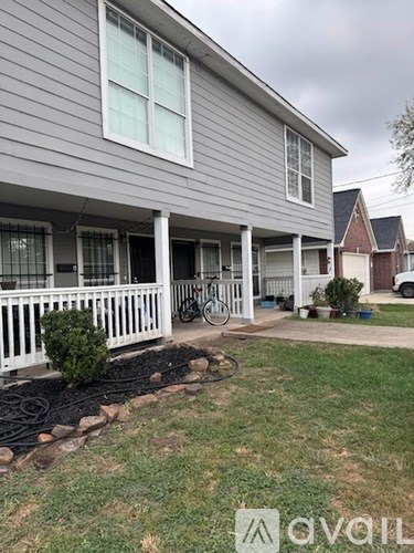 A grey house with a white porch and a bicycle parked on the front.