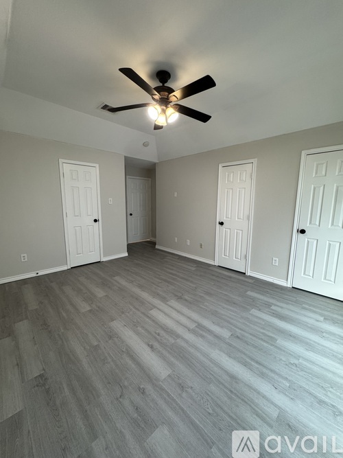 A room with a ceiling fan and wooden flooring.