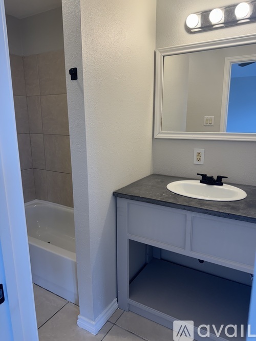 A bathroom with a sink, mirror, and a bathtub.