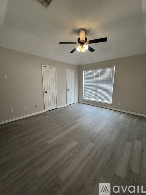 A room with a ceiling fan and wooden flooring.