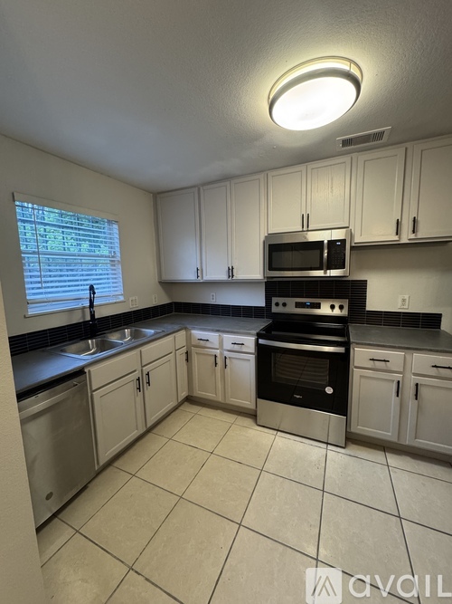 A kitchen with white cabinets and a black stove top oven.