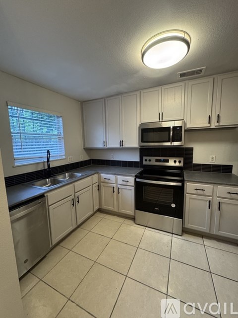 A kitchen with white cabinets and a black stove top oven.