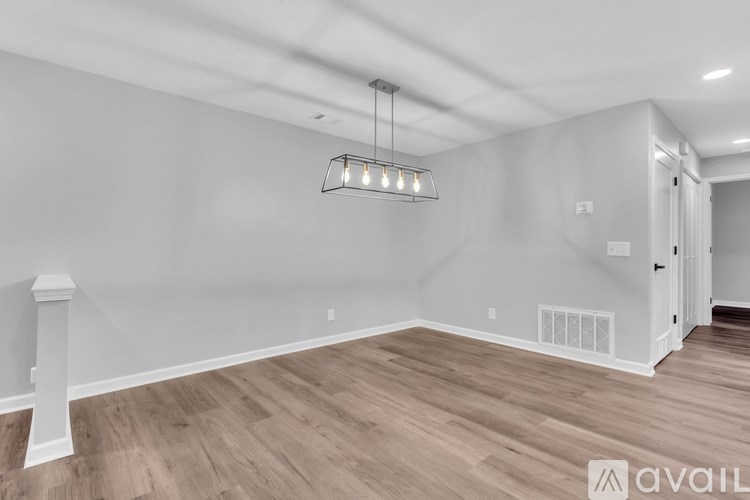 A room with wooden flooring and a light fixture hanging from the ceiling.