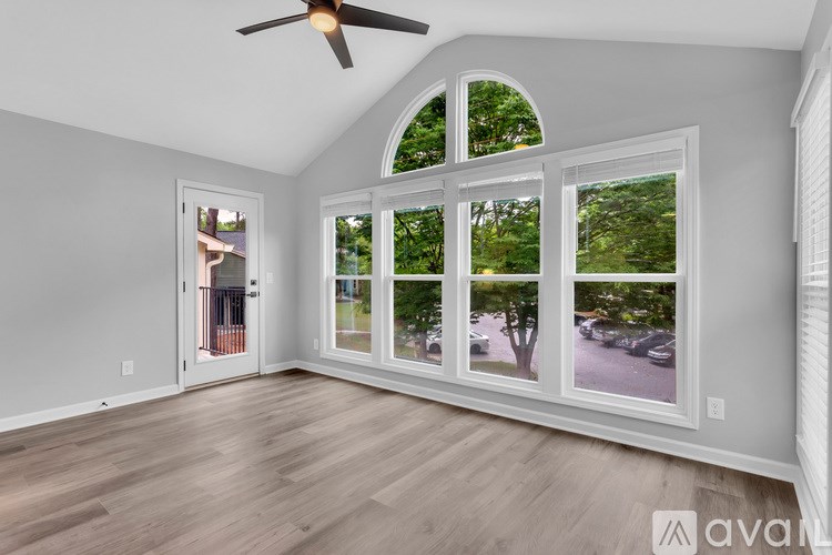 A room with a fan and a window showing a view of a street.
