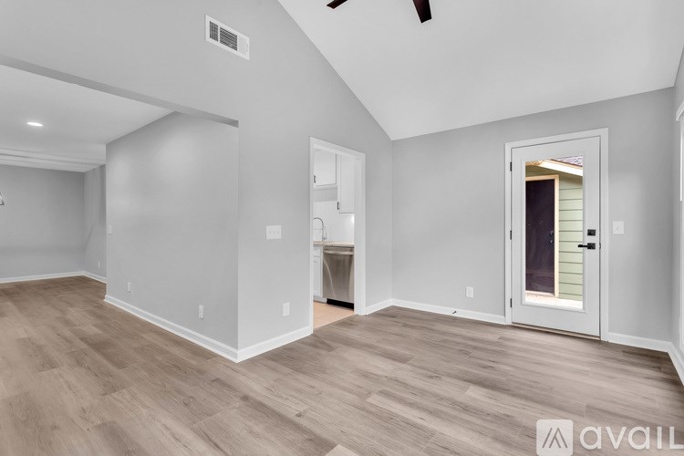 A spacious room with a door on the right and a ceiling fan on the left.