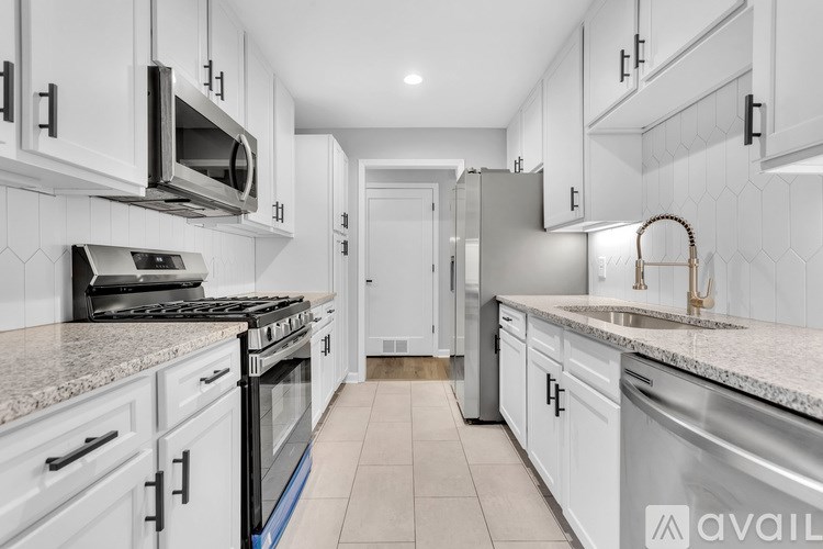 A modern kitchen with white cabinets and a blue tile backsplash.