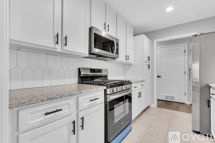 A kitchen with white cabinets and a granite countertop.