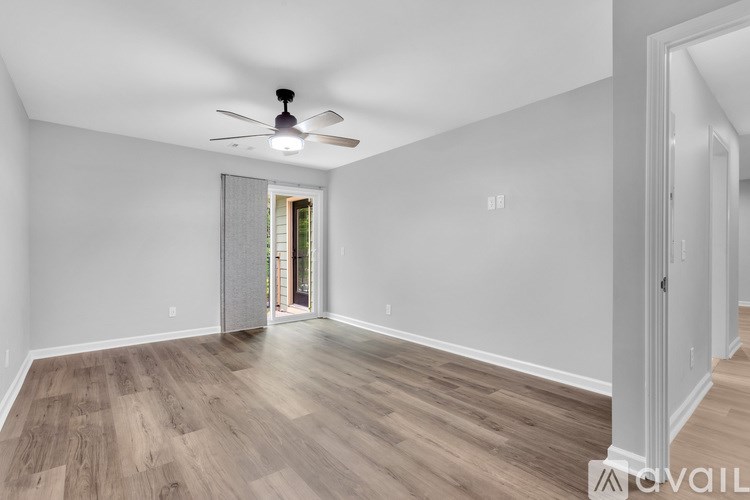 A spacious room with a ceiling fan and wooden flooring.