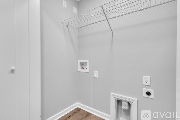 A room with a white wall and a wire shelf.