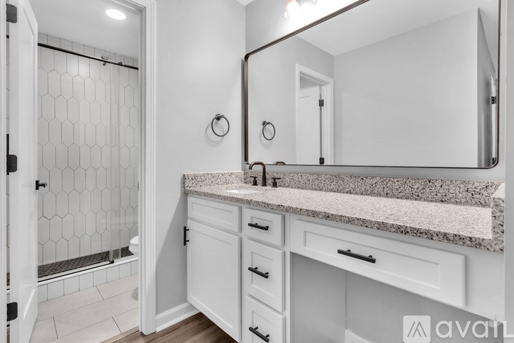 A bathroom with a marble countertop and white cabinets.