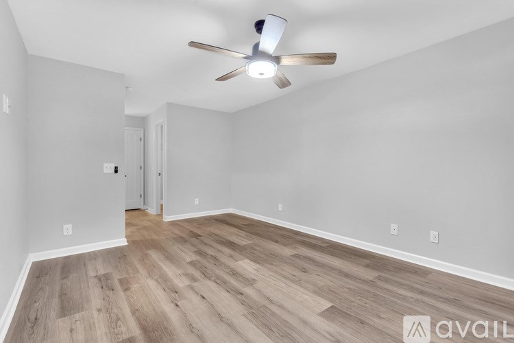 A room with a ceiling fan and wooden flooring.