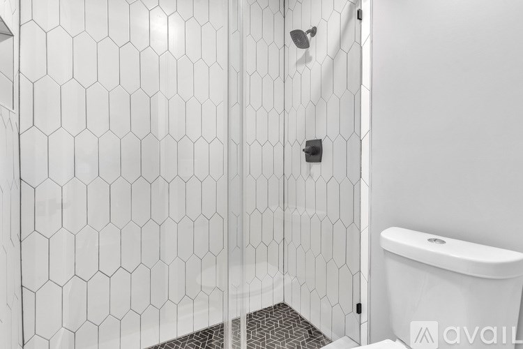 A white bathroom with a hexagonal tile shower and a white toilet.