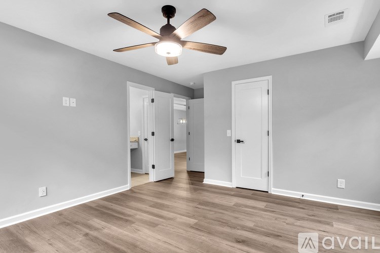 A room with a ceiling fan and wooden flooring.