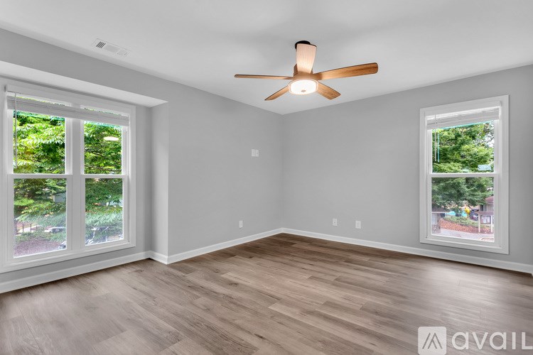 A room with a ceiling fan and two windows.